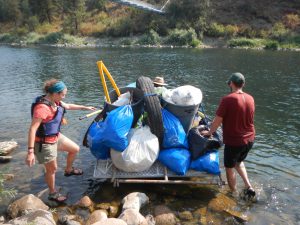 Two students with a pile of trash on a boat