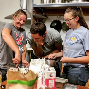 Three students mix ingredients in a bowl